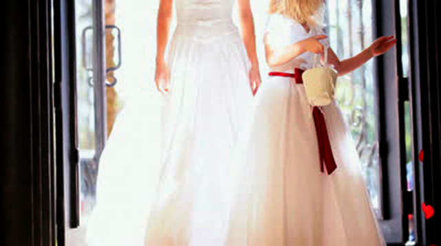 stock-footage-pretty-blonde-flower-girl-scattering-red-rose-petals-in-front-of-walking-bride-sun-lens-flare